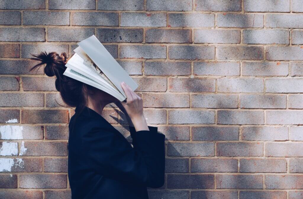 本を顔に覆いかぶす女性